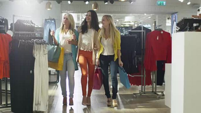 三个快乐的女孩正穿着五颜六色的衣服穿过一家服装店。