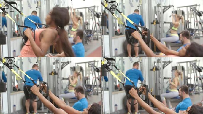 年轻女子在繁忙的健身房用阻力带训练