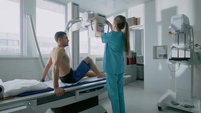 在医院里，男人坐在床上，女技术员调整x光机扫描他的腿是否受伤。扫描骨折、四肢骨折、癌症或肿瘤。拥有技