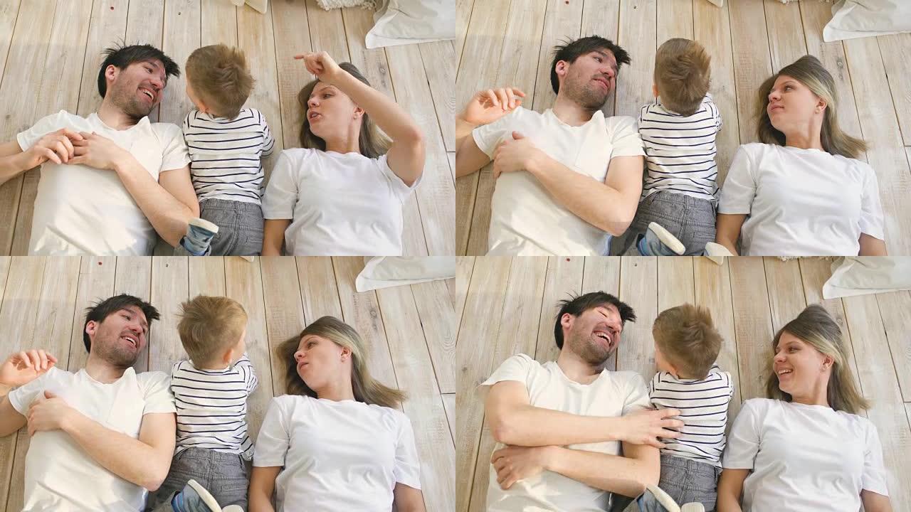 英俊的父亲和母亲躺在地板上玩耍和拥抱他们的小儿子的俯视图