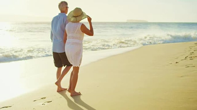 日落时在海滩上散步的快乐夫妇