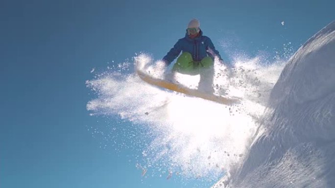 慢动作: 滑雪者在阳光明媚的山区的冬季在粉雪中跳跃