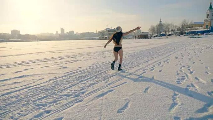 一个穿着比基尼的长发女人在雪地上跳着。