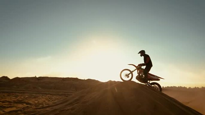 专业摩托车越野赛摩托车骑手跳过沙丘和越野赛轨道。在太阳落山时拍摄的废弃采石场。