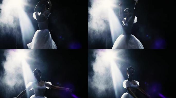 一位美丽的年轻芭蕾舞演员在聚光灯下优雅地旋转。粉末和烟雾在她周围的黑暗中闪耀。她穿着白色短裙，在灯光