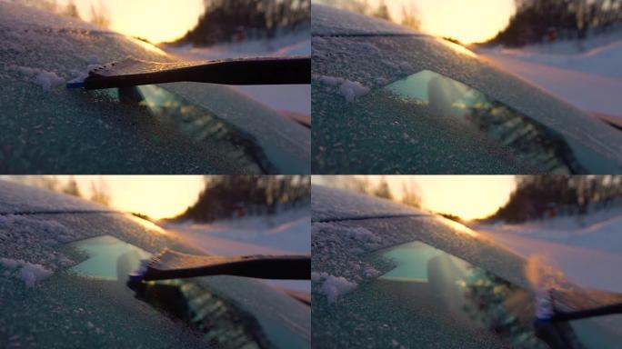 慢动作特写: 在金色日出时清理车窗上的早晨霜