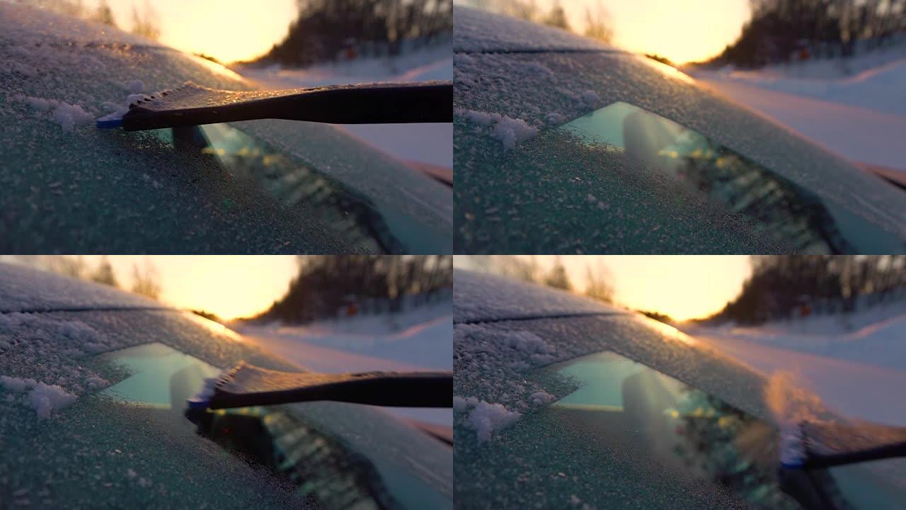 慢动作特写: 在金色日出时清理车窗上的早晨霜