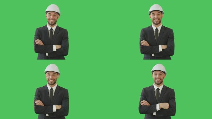 英俊的微笑商人穿着量身定制的西装，双臂交叉着安全帽。背景是绿屏模型。