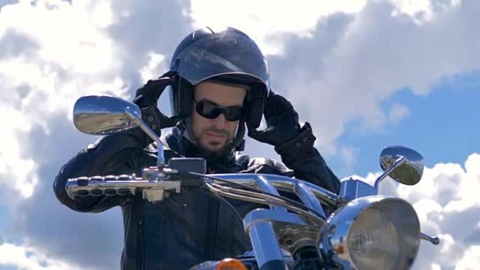 一个男人坐在他的自行车上，脱下头盔。摩托车手肖像。