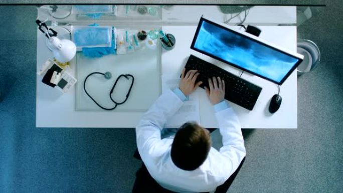 坐在办公桌前的医生的俯视图，分析患者的x射线。他在一份文件上写下病人的诊断信息。