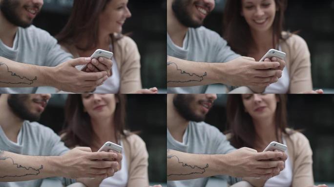 年轻微笑的女人和男人在户外使用手机。
