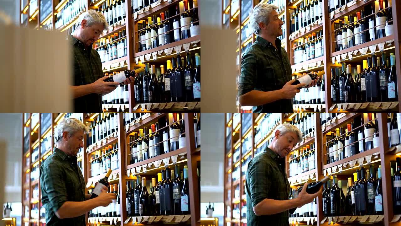 中年男子在一家葡萄酒商店看着不同的瓶子