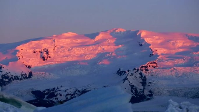 雪山山峰上美丽的粉色日出之光。