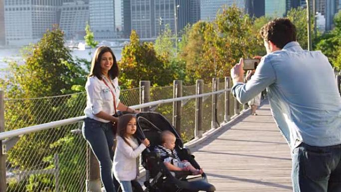 年轻的家庭在曼哈顿的行人天桥上拍照