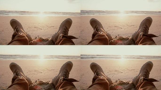 黎明时分，穿着棕色靴子的2英尺在沙滩上休息