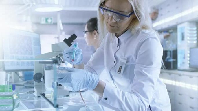 医学研究科学家在用注射器注射的实验室小鼠上测试疫苗实验药物。她在一个明亮的现代实验室工作。