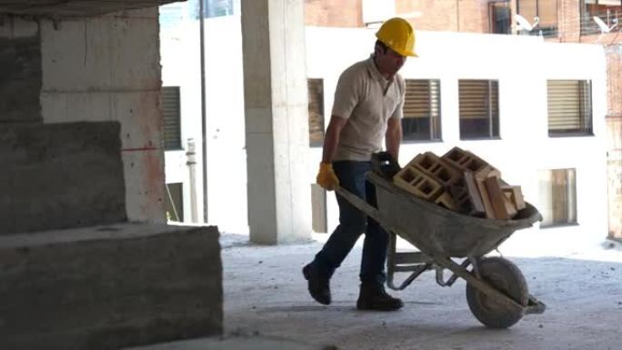 蓝领工人在建筑工程中推着装满砖头的独轮车