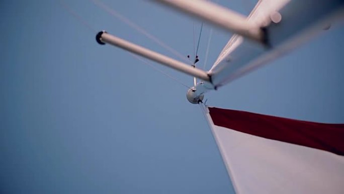在明亮的夏日，白色和红色的帆在风中挥舞。速度帆板的特写视图。阳光普照
