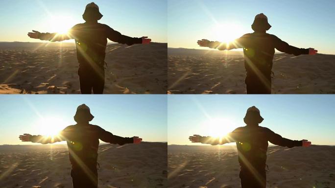 黑兜帽在沙漠日落时张开双臂。