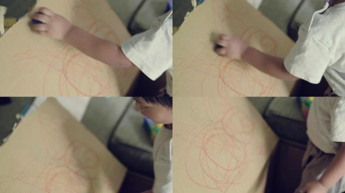 亚洲蹒跚学步的男孩练习用蜡笔画画