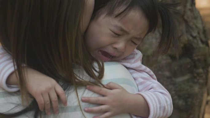 负面情绪亚洲母亲在花园里抱着哭泣的女婴