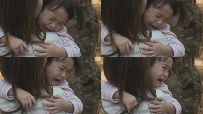 负面情绪亚洲母亲在花园里抱着哭泣的女婴
