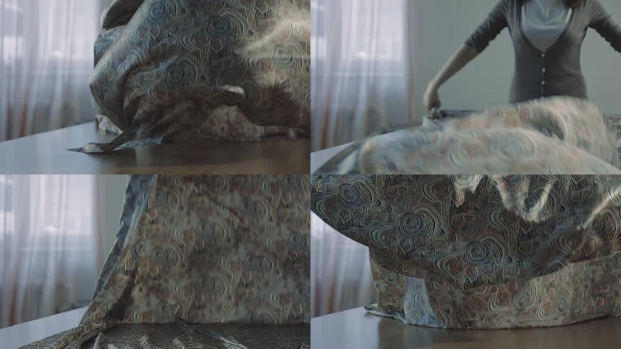 织物漂亮的慢动作落在桌子上。女性的手用布工作。