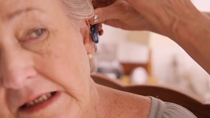 女医生在高级女性耳朵中插入助听器