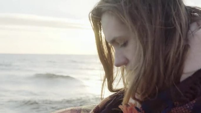 年轻迷人的女性的肖像，用格子站在海边，看着远处，思考