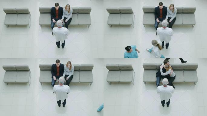 在医院高角度拍摄，年轻夫妇坐在大厅等待检查结果，从他们的医生那里收到好消息。年轻人生活中的快乐时刻。
