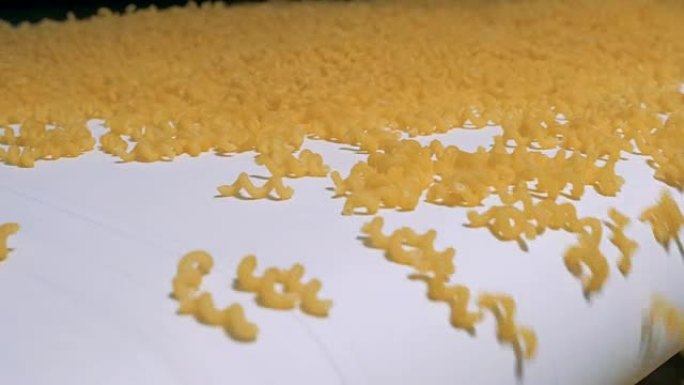 一堆黄色的螺旋通心粉沿着传送带移动。意大利面、通心粉、面条、意大利面生产线。
