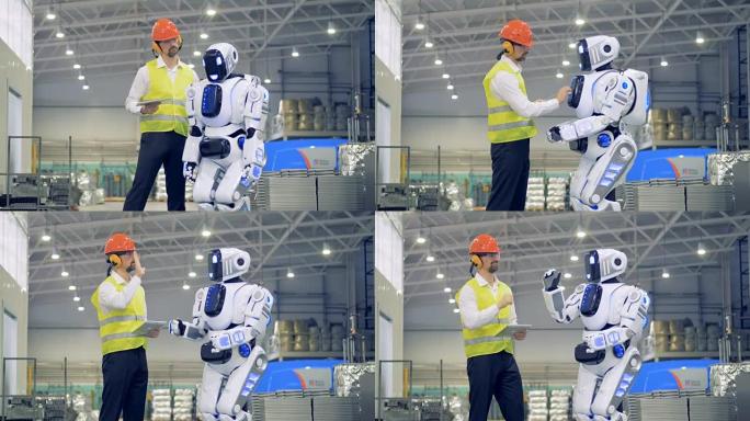 男性工人打开机器人，然后在工厂里迎接它。4K。