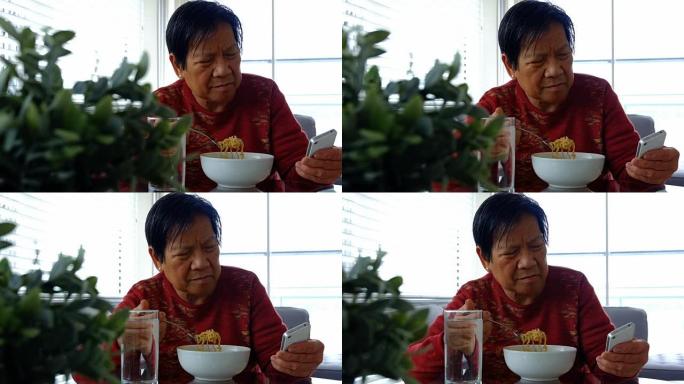 老年妇女在吃饭时使用手机