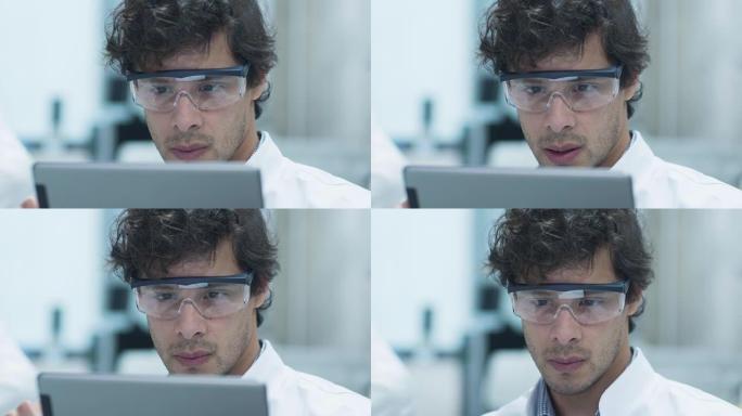 在实验室中使用平板电脑的安全眼镜中的拉丁裔科学家。