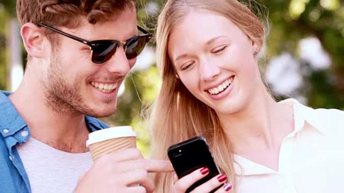 微笑的臀部夫妇使用智能手机