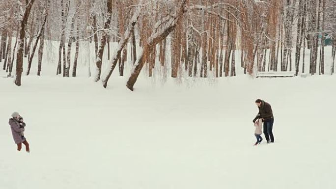 年轻的家庭在雪地里玩耍和玩耍