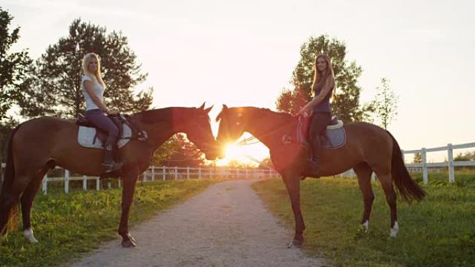 慢动作: 两匹马与漂亮的女骑手在日落时彼此面对