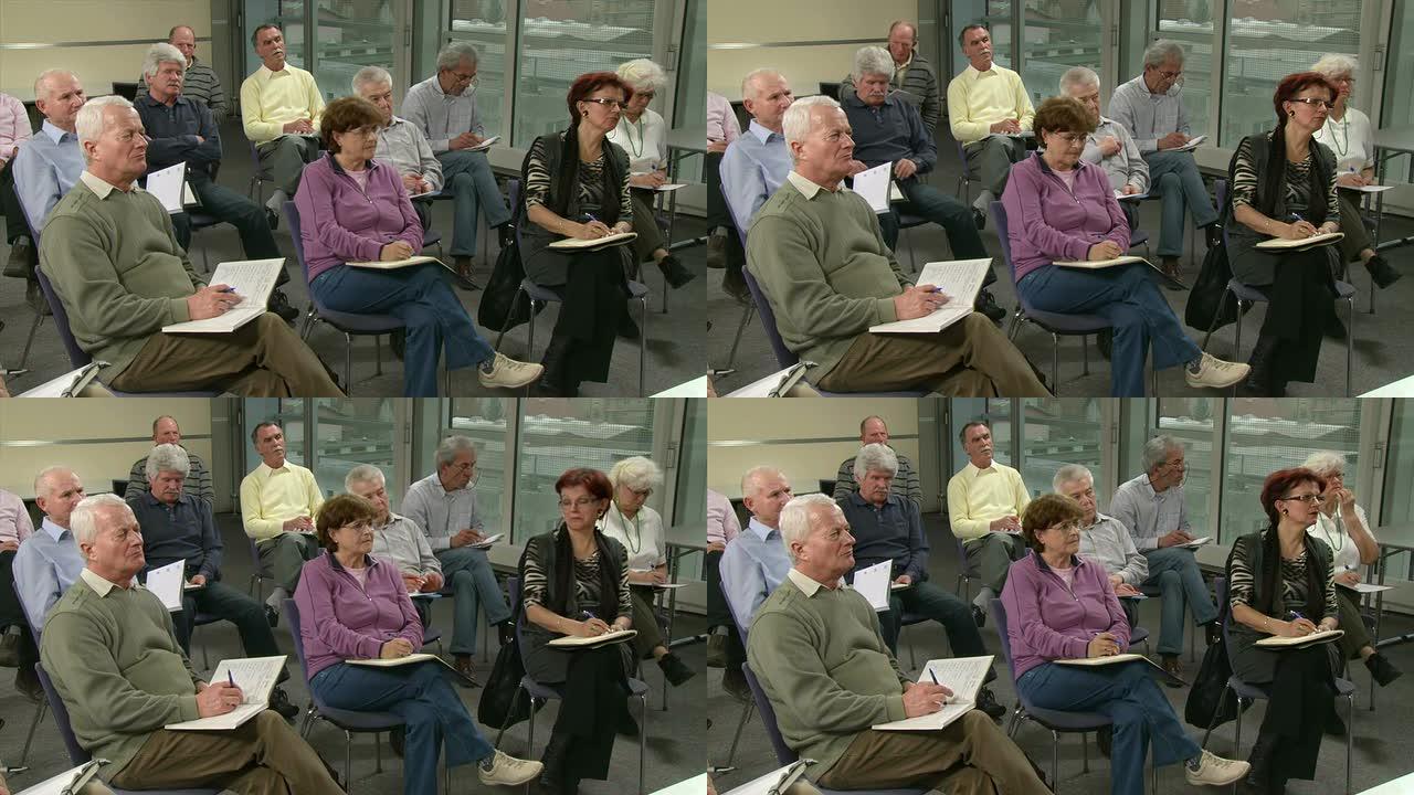高清: 老年人在研讨会上写笔记