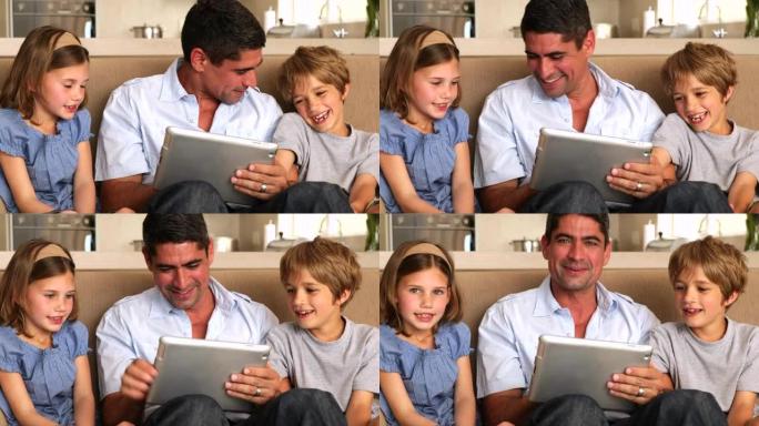 可爱的孩子用平板电脑和父亲在沙发上