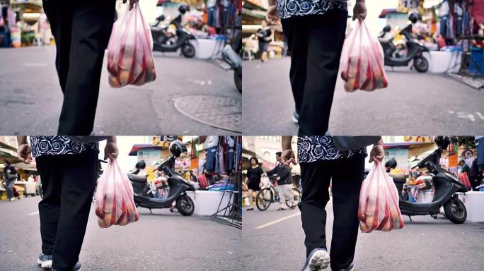 老妇人提着购物袋走在街上