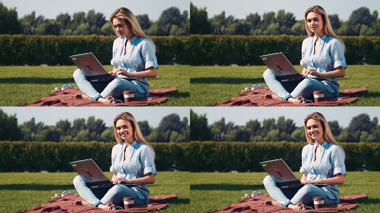 公园里用笔记本电脑盖着微笑的漂亮女孩