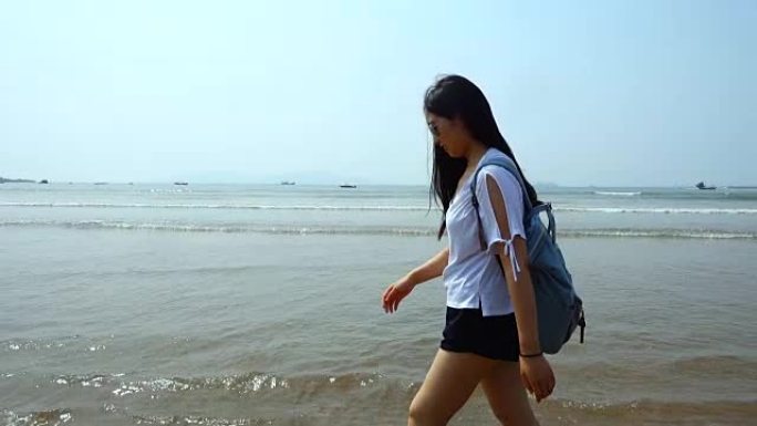 年轻的女游客，背着背包在海边散步，慢动作