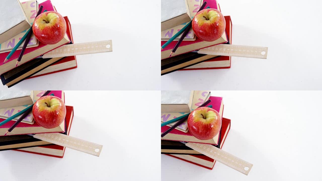 白色背景下的书籍、彩色铅笔和苹果