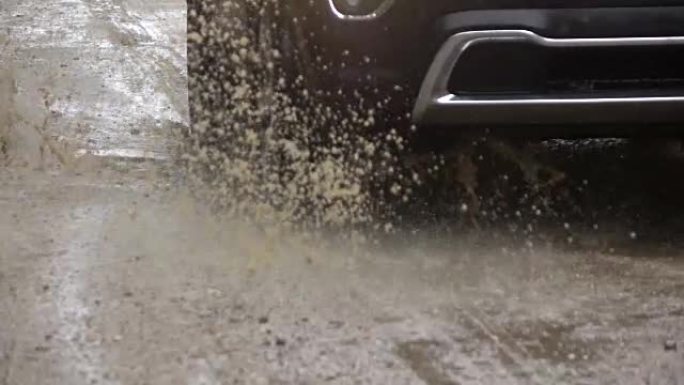 慢动作特写: SUV汽车在土路上的深雨水坑上行驶