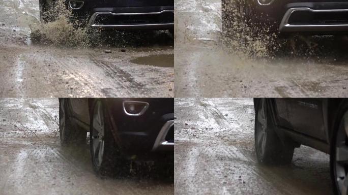 慢动作特写: SUV汽车在土路上的深雨水坑上行驶