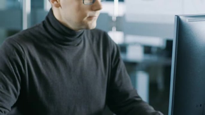 年轻的男性工业工程师在个人电脑上工作。明亮现代办公室里英俊聪明的男人。
