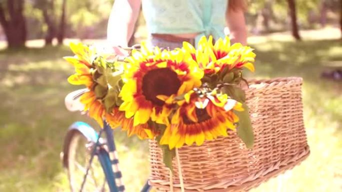自行车篮子里的向日葵细节和公园里的女孩