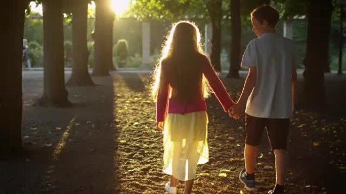 男孩和女孩手牵着手，在公园散步