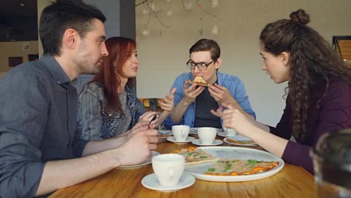 快乐的学生在nice舒适的咖啡馆里吃美味的披萨时分享新闻，打手势和大笑。美味的食物，开朗的人和外出就