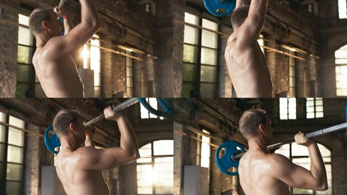 肌肉裸男在工业健身房大楼里举着沉重的杠铃，做着军事按压健身运动。